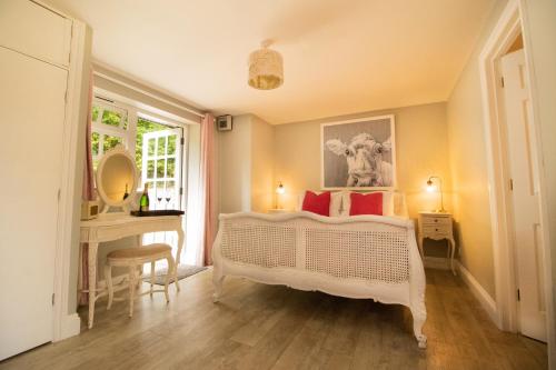 a bedroom with a white bed and a desk and a window at Boscundle Manor in St Austell