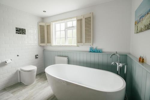 a bathroom with a white tub and a toilet at Boscundle Manor in St Austell