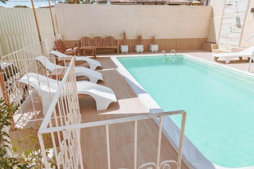 a swimming pool with chairs next to a building at Pousada Porto Da Barra in Porto Seguro