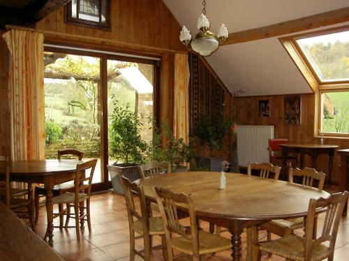 ein Esszimmer mit Tischen, Stühlen und Fenstern in der Unterkunft Le Verger Sous Les Vignes in Villeferry