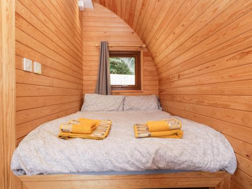 a bed in a wooden cabin with two towels on it at Halmore Pod in Berkeley