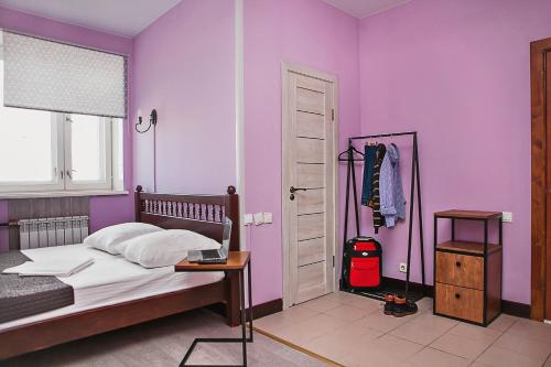 a bedroom with purple walls and a bed with a table at Hunter's Hut in Novosibirsk