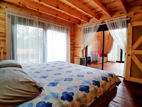 a bedroom with a bed and a large window at Hermosa Cabaña en Mazamitla a 1km del centro - Hermosa vista - Cómodas habitaciones - Todo cerca in Mazamitla