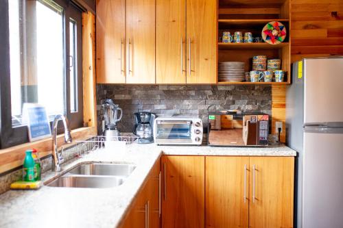 a kitchen with a sink and a refrigerator at Hermosa Cabaña en Mazamitla a 1km del centro - Hermosa vista - Cómodas habitaciones - Todo cerca in Mazamitla