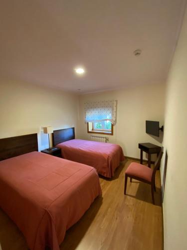 a hotel room with two beds and a chair at Casa Santa Catarina in Montalegre