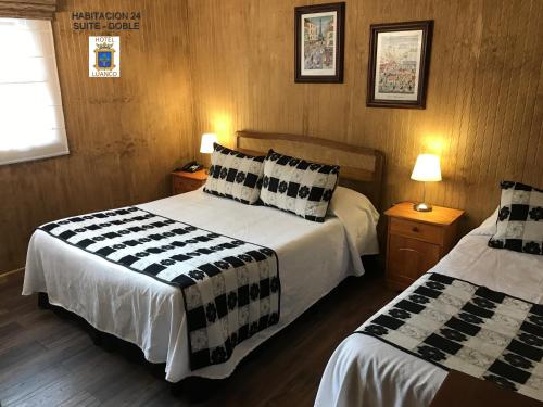 a hotel room with two beds and two lamps at Hotel Luanco in Temuco