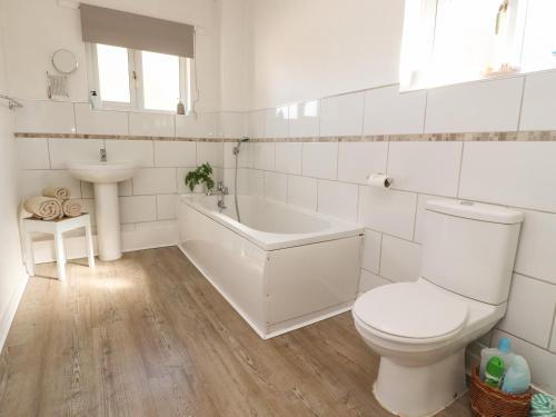 a bathroom with a toilet and a tub and a sink at Springfield Cottage in Chipping