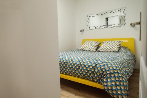 - une chambre avec un lit jaune et un miroir dans l'établissement CHARMANT T3 JAUDE + TERRASSE ET GARAGE, à Clermont-Ferrand