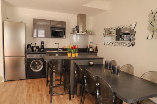 une cuisine avec une table avec des chaises et un réfrigérateur dans l'établissement CHARMANT T3 JAUDE + TERRASSE ET GARAGE, à Clermont-Ferrand