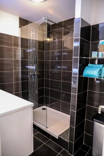 La salle de bains est pourvue d'une douche avec du carrelage noir. dans l'établissement CHARMANT T3 JAUDE + TERRASSE ET GARAGE, à Clermont-Ferrand