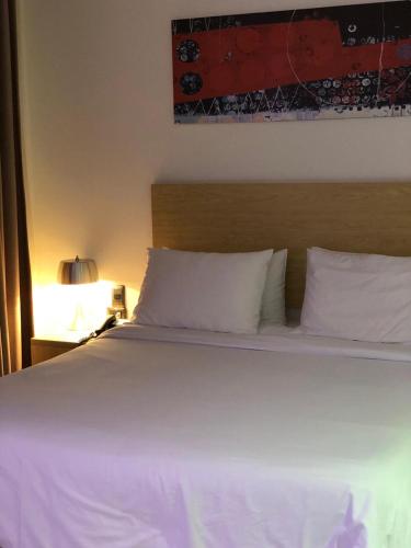 a bed with white sheets and pillows next to a lamp at Radisson Diamond Barranquilla in Barranquilla