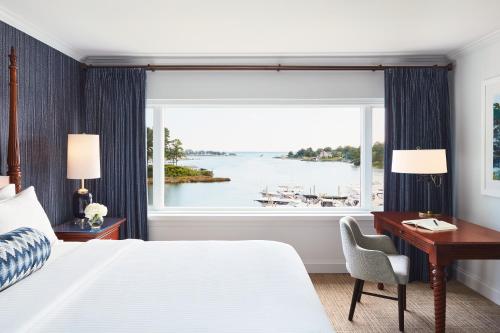 a bedroom with a bed and a desk and a large window at The Tides Inn in West Irvington