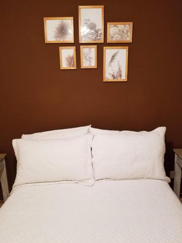 a bedroom with a white bed with four pictures on the wall at Boedo Tango Apartment in Buenos Aires