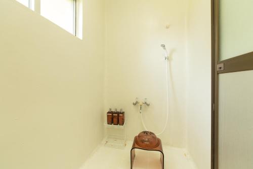 Baño blanco con silla y ducha en Villa Itona, en Ishigaki Island