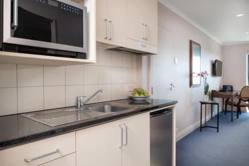 a kitchen with a sink and a microwave at The Spencer Hotel in Auckland