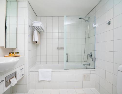 a white bathroom with a shower and a sink at The Spencer Hotel in Auckland