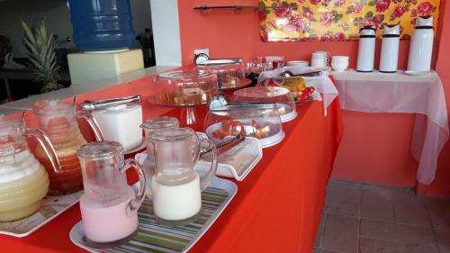 einem roten Tisch mit Milch in Glasmason-Gläsern in der Unterkunft Pousada Recanto do Sol e Mar in Porto De Galinhas