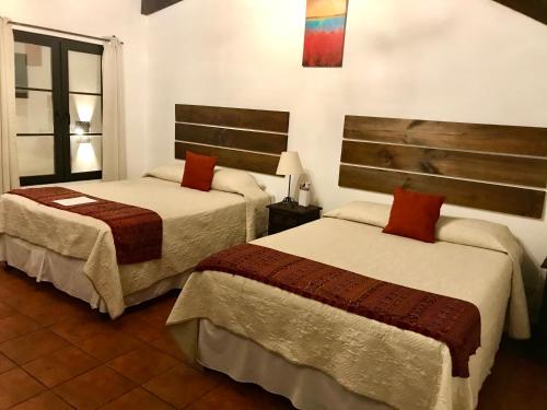 a hotel room with two beds and a window at Hotel la Galería in Antigua Guatemala