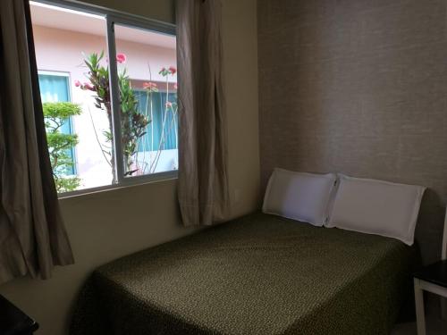 Un dormitorio con una cama y una ventana con una planta en Casa de temporada Marlete, en Florianópolis