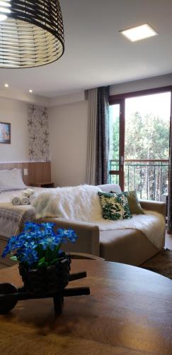 a bedroom with a bed and a table with flowers on it at Flat Vista Azul - Pedra Azul ES in Pedra Azul