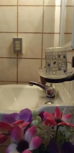 a bathroom with a sink with flowers in it at Hostal Tunquelen in Valparaíso
