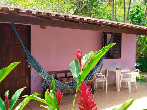 a porch of a house with a hammock and a table at Pousada Sitio das Flores in Trindade
