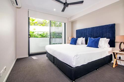 a bedroom with a large bed with a blue headboard at Hedge Apartments by CLLIX in Buddina