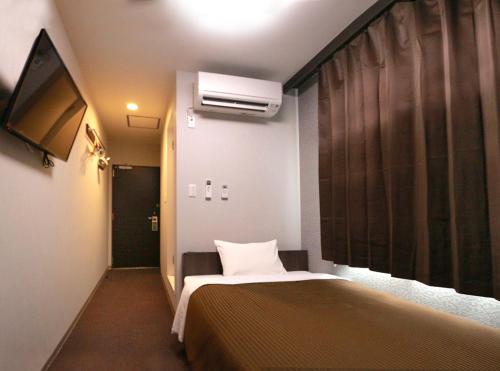 a hotel room with a bed and a tv at Hotel Trend Fukuyama Ekimae in Fukuyama