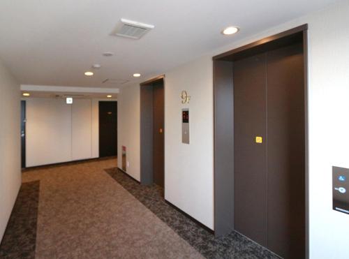 a hallway of an office building with dark doors at Hotel Trend Fukuyama Ekimae in Fukuyama