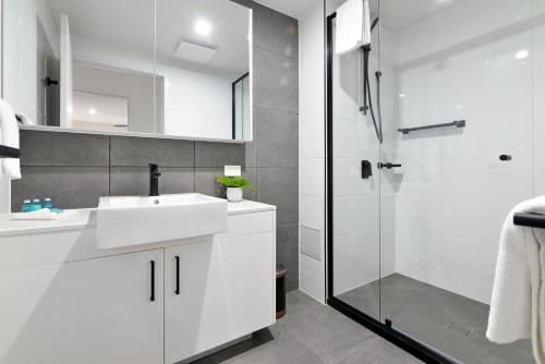 uma casa de banho com um lavatório branco e um chuveiro em Hedge Apartments by CLLIX em Buddina