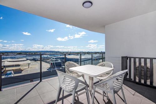 a table and chairs on a balcony with a view of a boat at Hedge Apartments by CLLIX in Buddina
