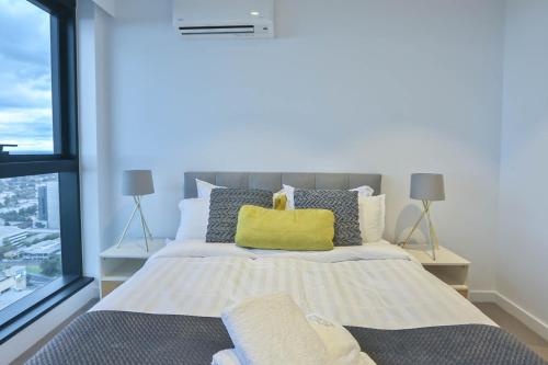 a bedroom with a bed with a large window at Box Hill Central Sky One Apartment in Box Hill