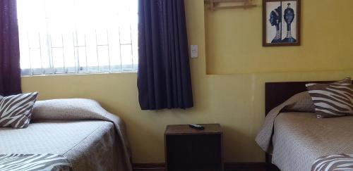 a bedroom with two beds and a window at Hostal Tunquelen in Valparaíso