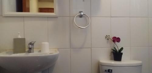 a white bathroom with a sink and a toilet at Hostal Tunquelen in Valparaíso