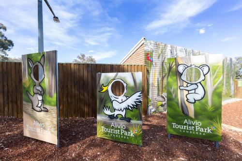 a fence with signs on it with a tennis park at Alivio Tourist Park Canberra in Canberra