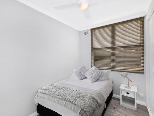 a white bedroom with a bed and a window at Golden Sands Apartment 10 in The Entrance