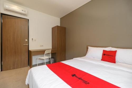 a bedroom with a bed with a red pillow on it at RedDoorz Syariah near Rumah Sakit Medika Dramaga in Bogor