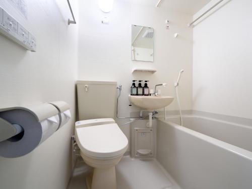 La'gent Inn Kesennuma في Kesennuma: حمام ابيض مع مرحاض ومغسلة