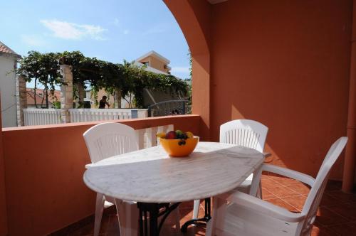 a white table and chairs with a bowl of fruit on it at Vila Apartments Lidija in Petrovac na Moru