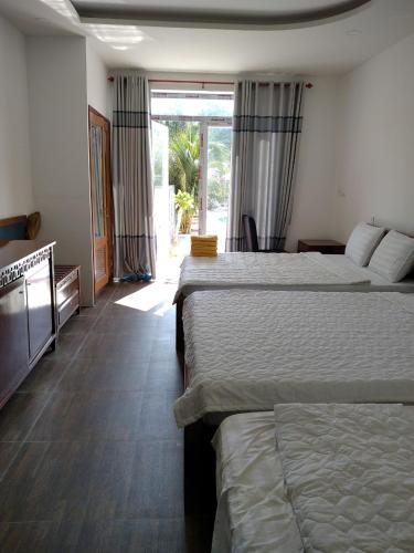 a hotel room with two beds and a large window at Resort Bao Anh Sunset Beach in Lagi