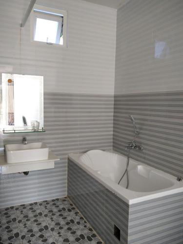 a white bathroom with a tub and a sink at Resort Bao Anh Sunset Beach in Lagi