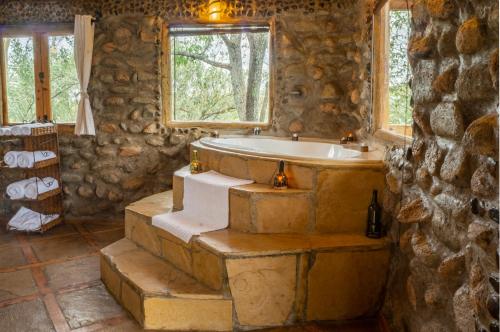 a stone bathroom with a tub and a window at Honeymoon Hut in Naivasha