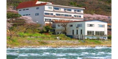 a building on a hill next to a river at Oyado Matsubaya / Vacation STAY 8065 in Obinata