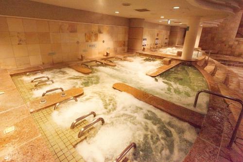 a large pool of water in a bathroom with surfboards at Ooedo Onsen Monogatari Hotel Reoma no Mori in Marugame