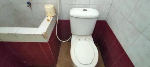 a bathroom with a white toilet in a room at Mangkuyudan Hotel Solo in Lawean