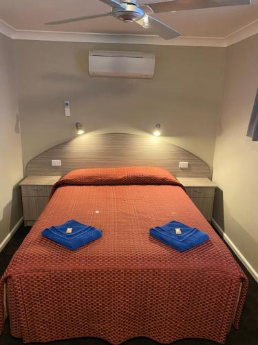 a bedroom with a bed with two blue towels on it at Bellview Motel in Narrabri
