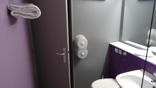 a bathroom with a door with a sink and a mirror at Initial by balladins Dieppe in Saint-Aubin-sur-Scie