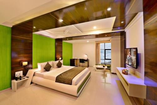 a bedroom with a bed and a green wall at Lords Inn Porbandar in Porbandar