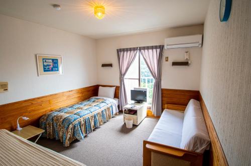 a hotel room with two beds and a television at Pension KUROSHIOMARU in Setouchi