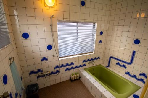 ein Bad mit einer grünen Badewanne und einem Fenster in der Unterkunft Pension KUROSHIOMARU in Setouchi